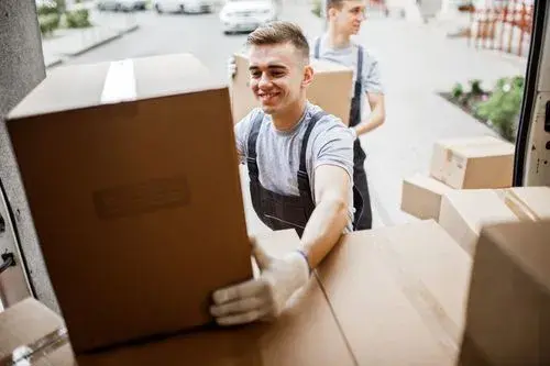A delivery man unloads packages from a truck with a smile, exemplifying efficient and cheerful service, enhanced by last mile delivery tracking.