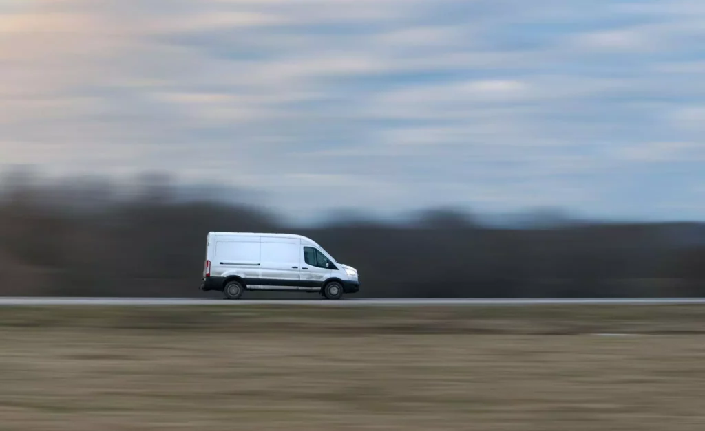 A wide shot of a white van speeding along the freeway