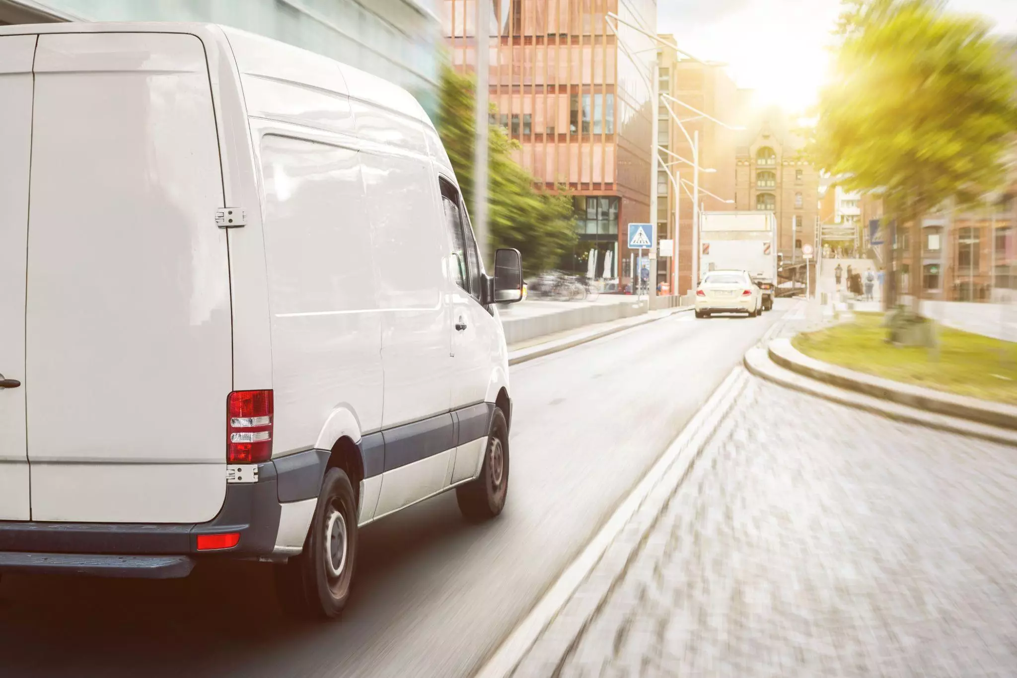 White cargo van driving through city streets, highlighting last-mile route optimization and on-time ETAs.
