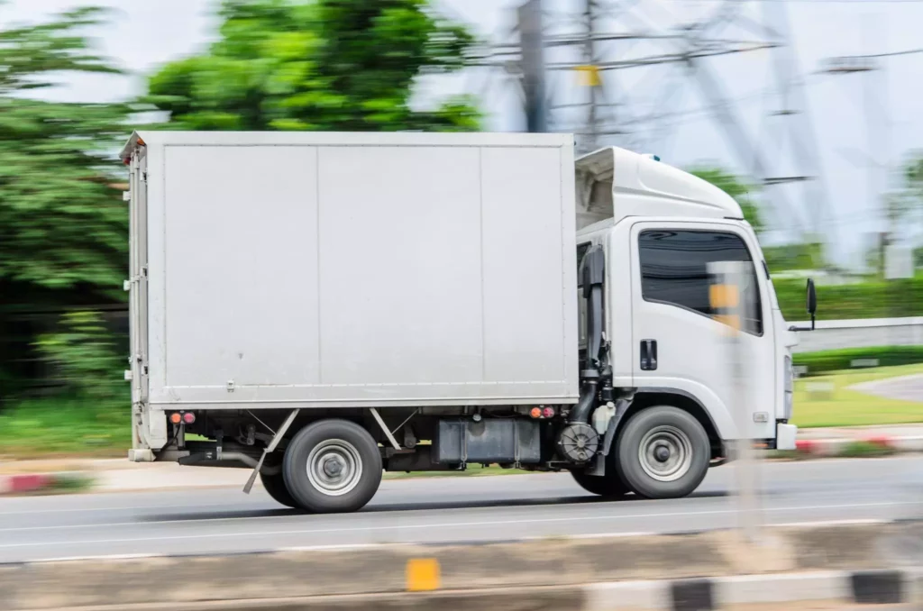 White delivery truck driving on an open highway, symbolizing logistics optimization and efficient route planning to improve logistics ROI