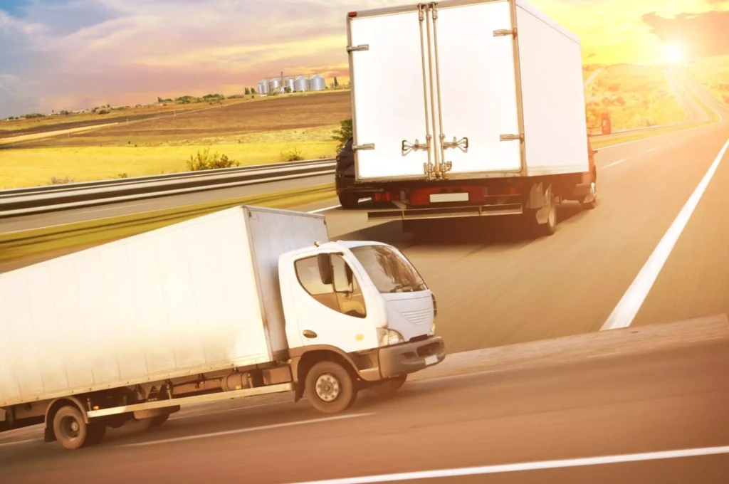 Two box trucks heading into sunset, dependable brand delivery with clear ETAs.