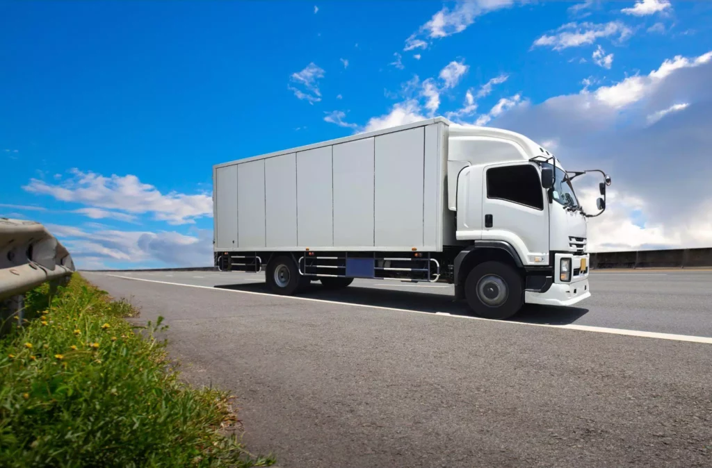 Long-haul white truck under clear sky, representing GPS, IoT sensors, and real time visibility in supply chains
