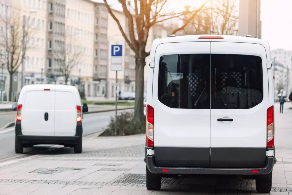 A rear shot of two white delivery vans parked on the pavement