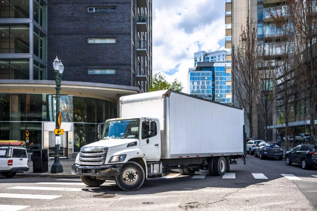 Box truck navigating city intersection, demonstrating exception alerts, rerouting, and customer notifications in real time