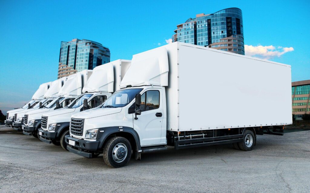 Row of box trucks near office towers, representing logistics optimization for fleet, network, and capacity planning.