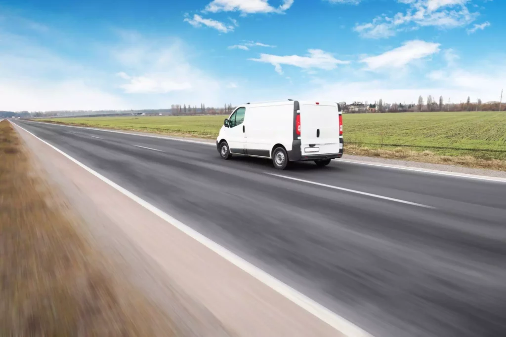 Compact delivery van on rural highway, highlighting resilient networks powered by real-time supply chain visibility