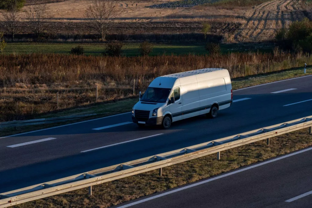 High-roof white van cruising at dusk beside fields, emphasizing safe, secure, and consistent delivery experiences
