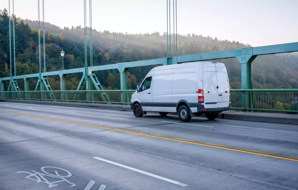 Delivery van crossing a bridge, symbolizing supply chain disruptions and logistical challenges in regional transport.