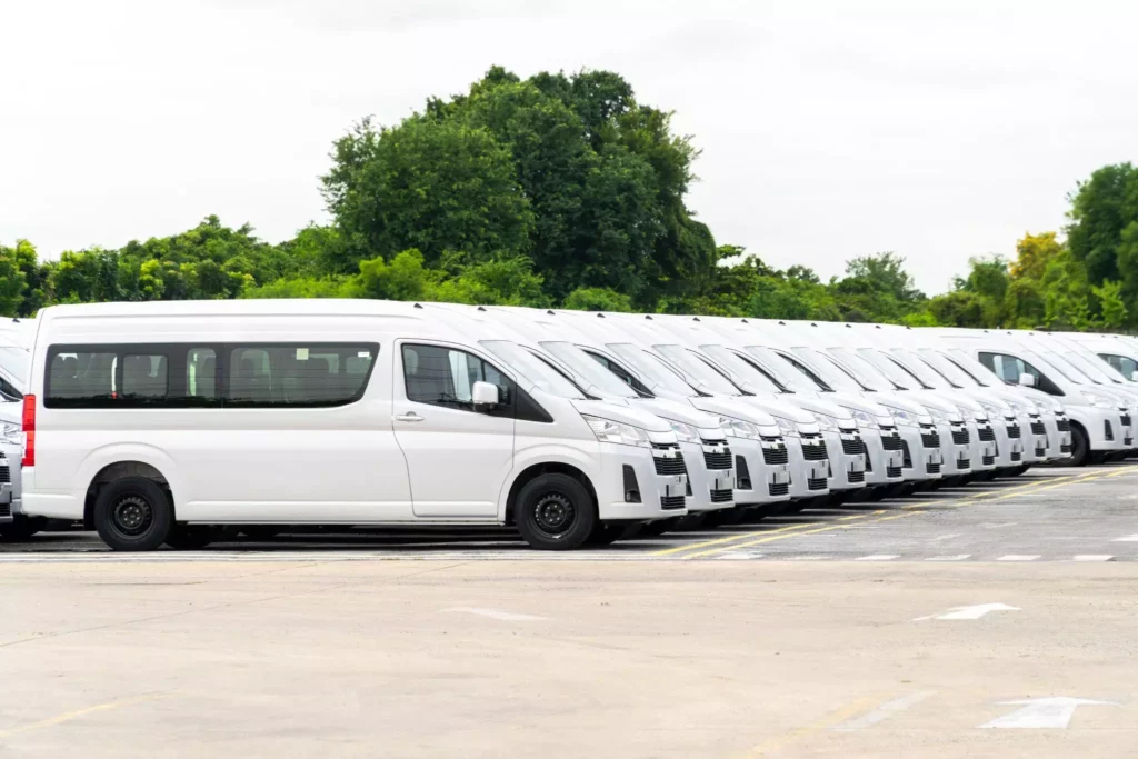 Row of identical white vans at depot, consistent fleet branding for a seamless delivery experience.