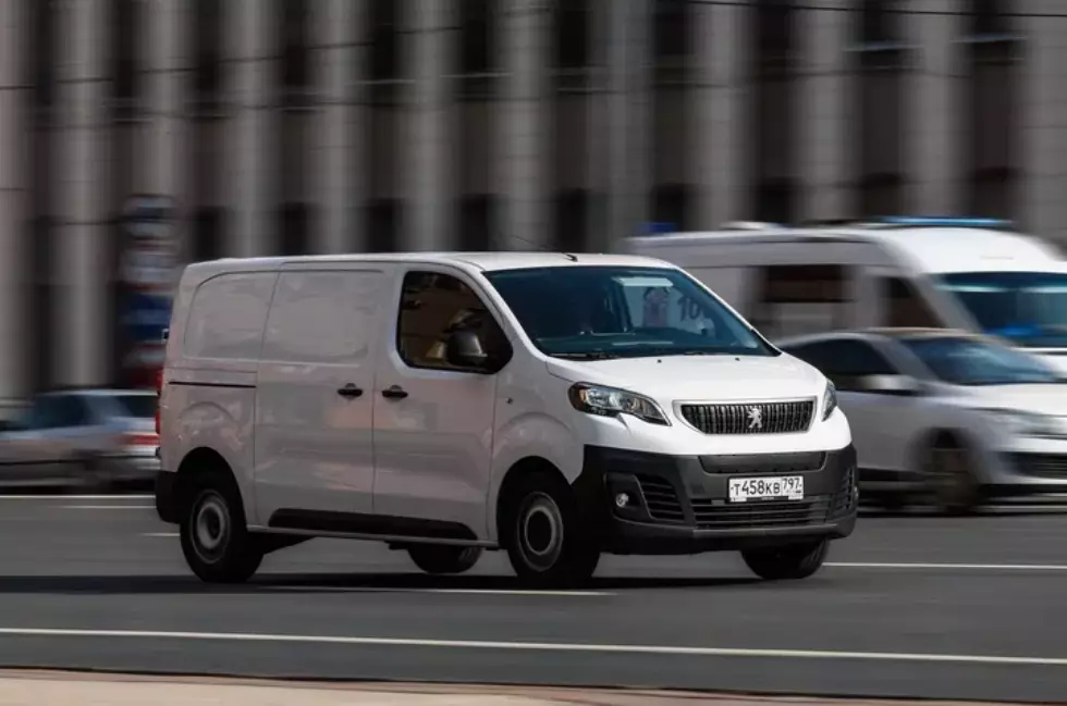 White delivery van driving through a busy city street, representing logistics optimization, efficient route planning, and improved logistics ROI with real-time tracking and fleet utilization