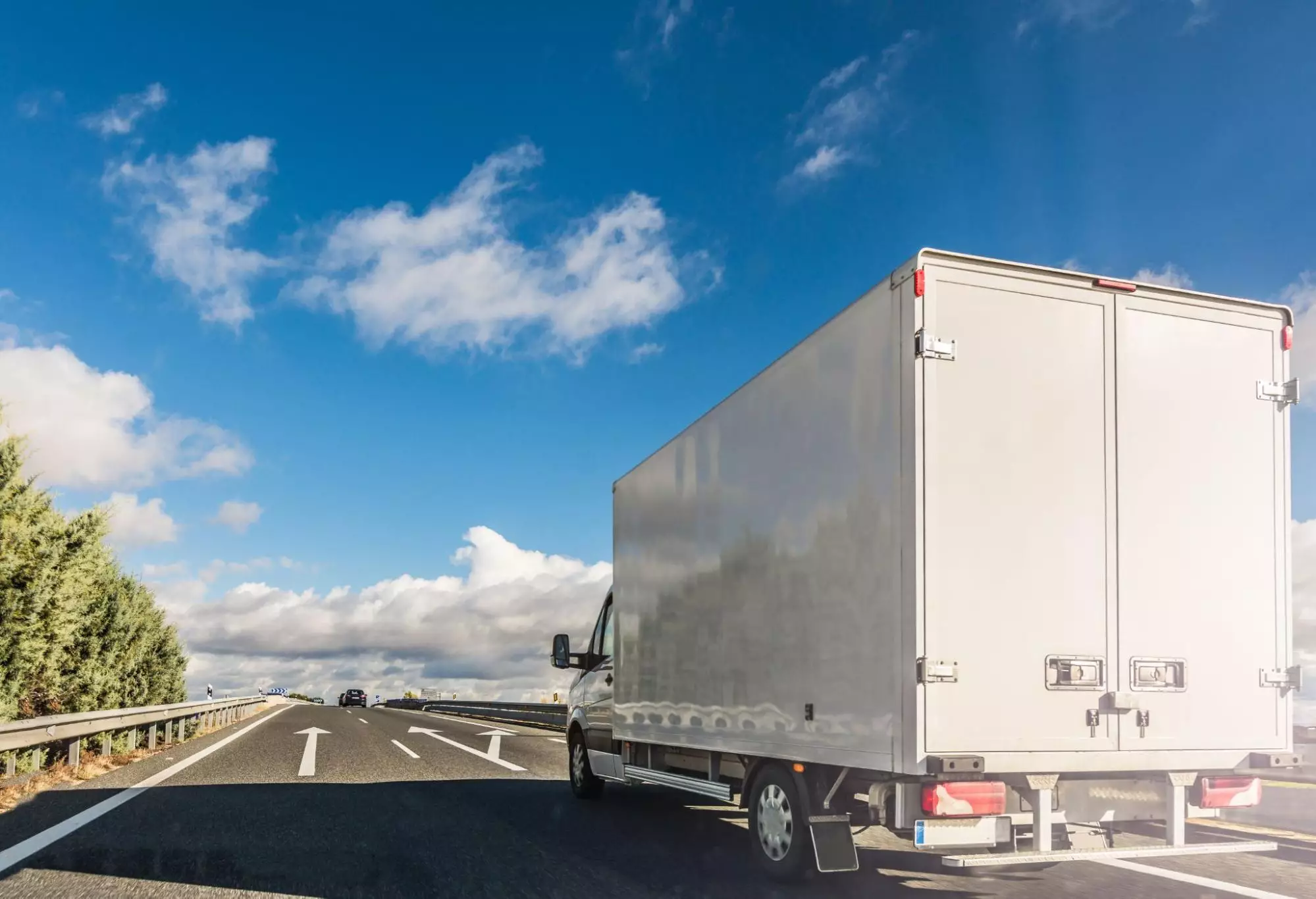 image1 Box truck merging on highway under blue sky.