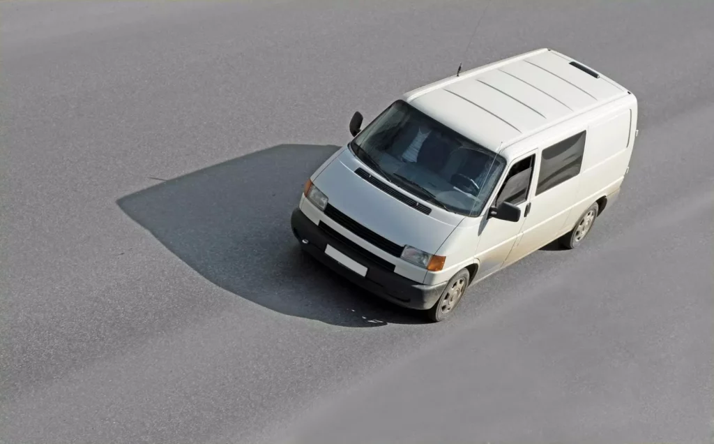 Compact white cargo van turning on a city road amid a logistics delay