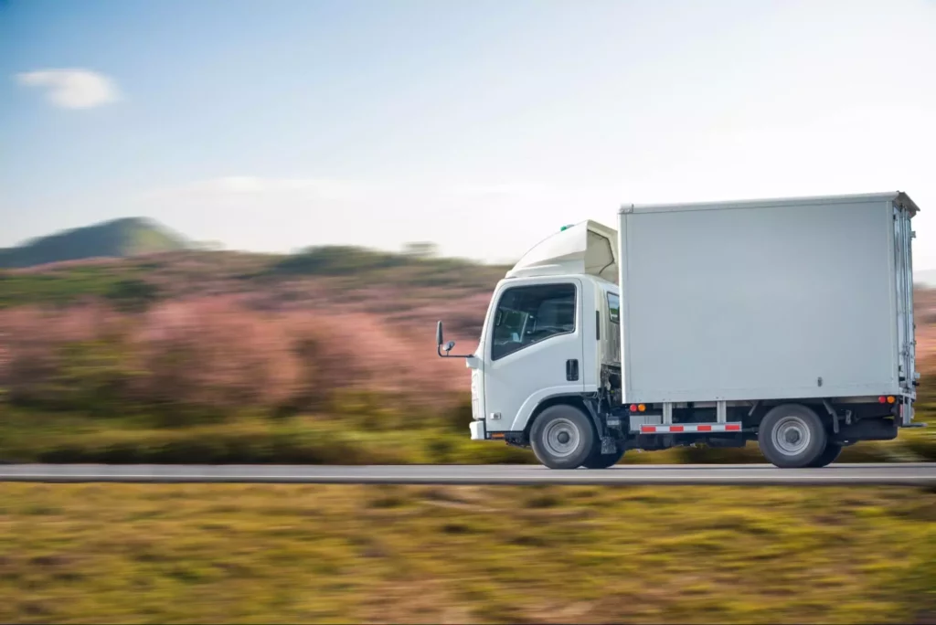 Light box truck in motion past countryside. 