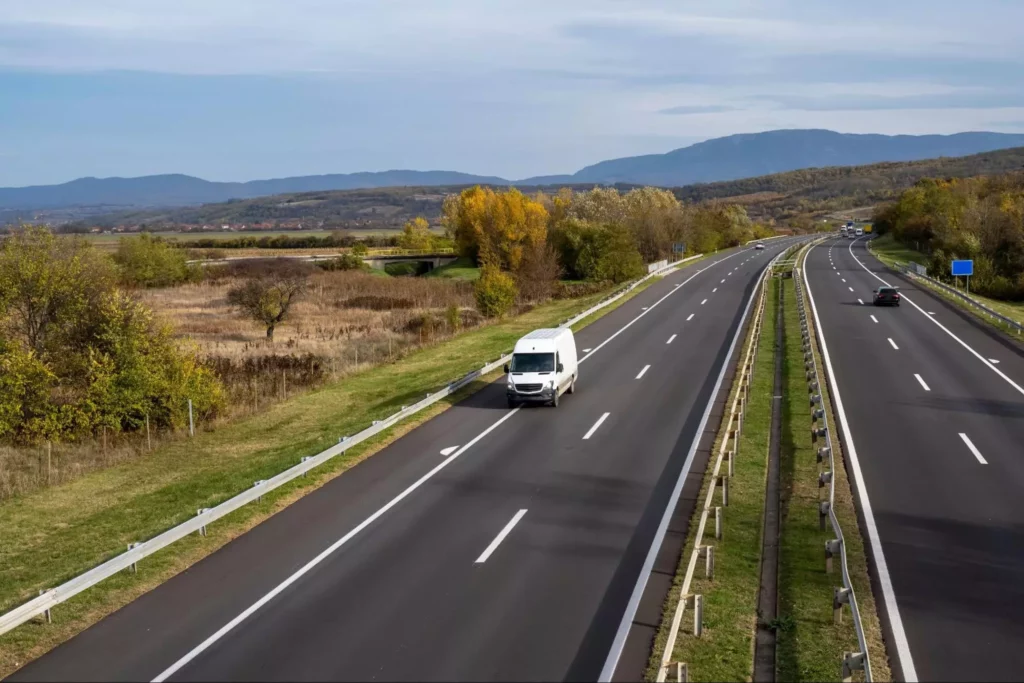 White delivery van driving on open road showing long-distance last-mile route
