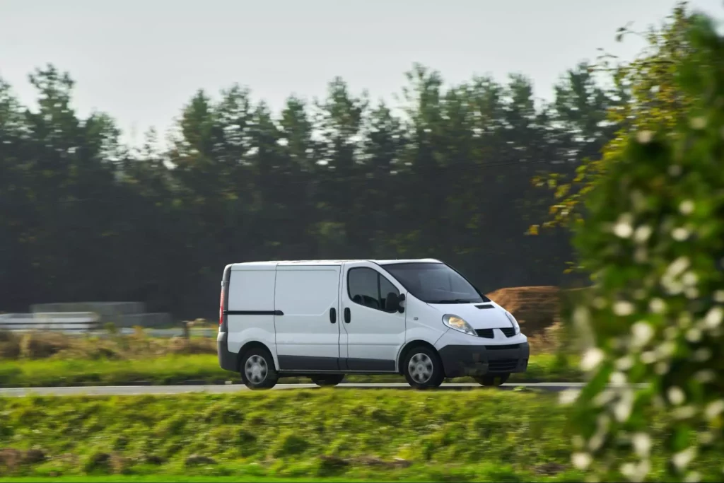 Compact white van on rural road. 