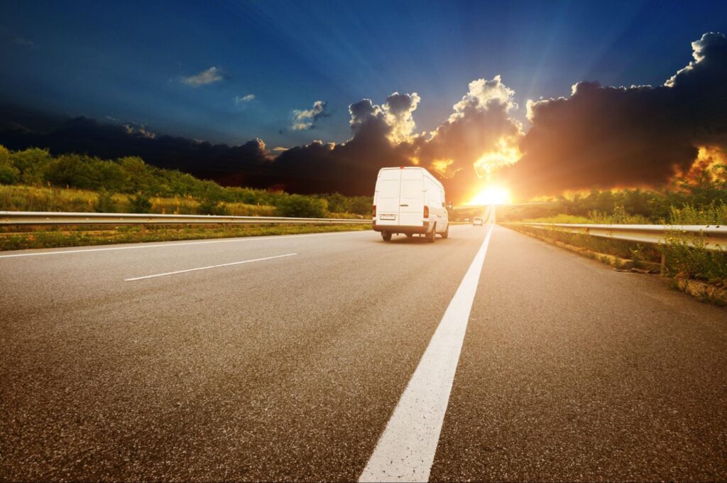 Rear view of white van on highway at sunset after a delivery delay notice