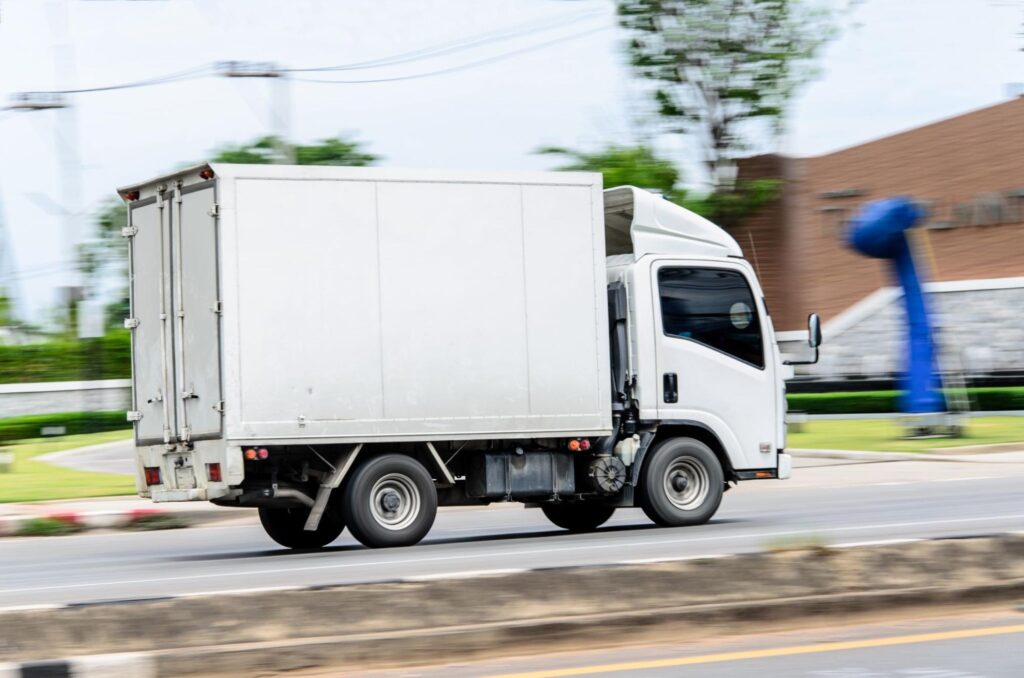 Medium box truck in motion through town.