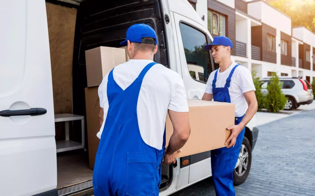 Two workers loading boxes into a white delivery van