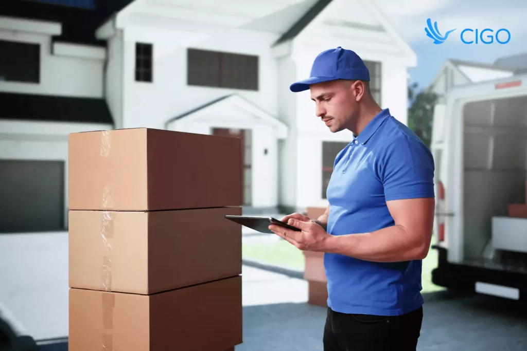 delivery worker reviewing orders on tablet next to packages