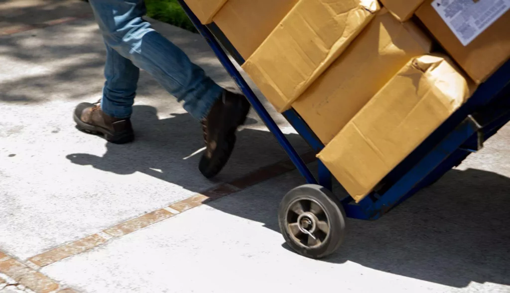 Close-up of a dolly wheel rolling as packed boxes are being transported
