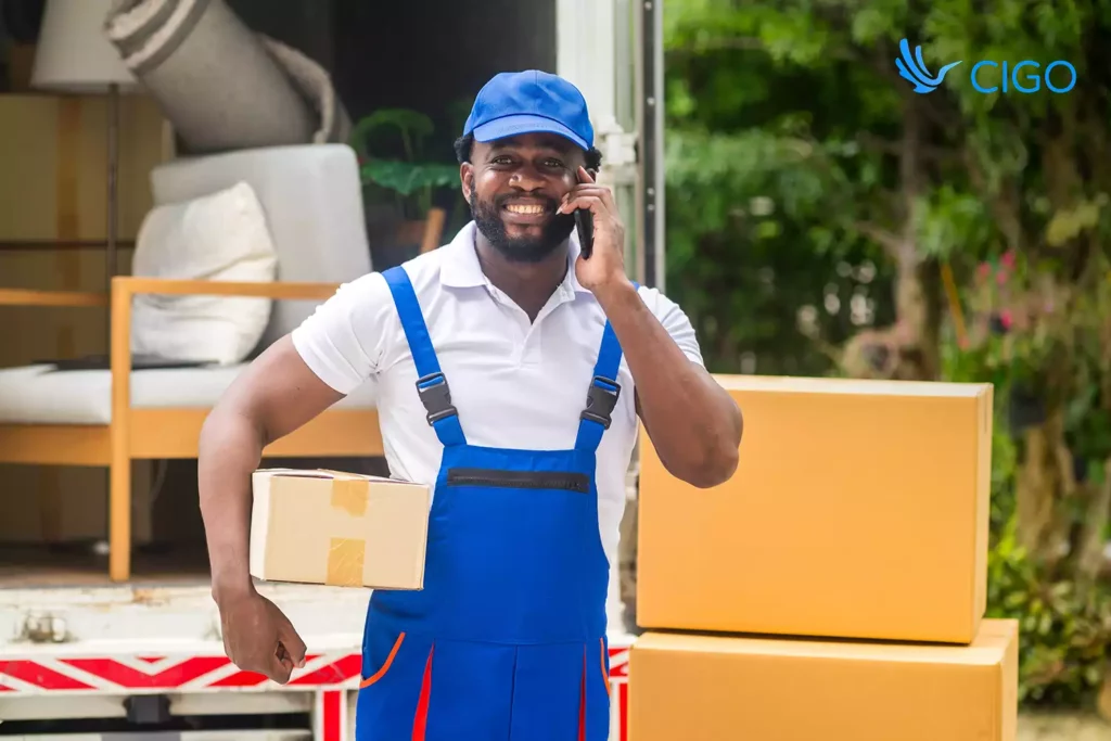 Courier on phone holding a package by truck