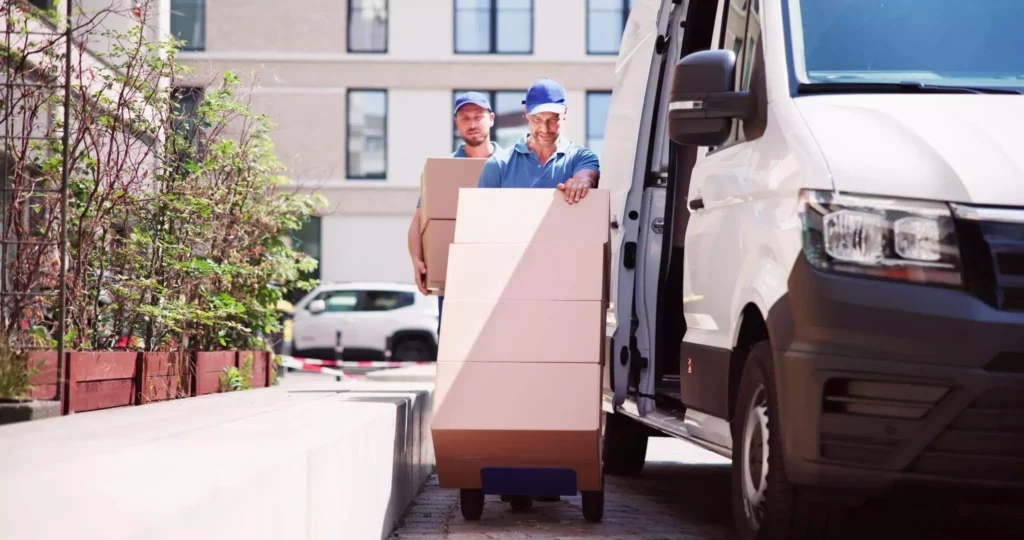 Two delivery professionals unloading boxes with a hand truck, representing streamlined operations and coordinated routing through last-mile delivery software