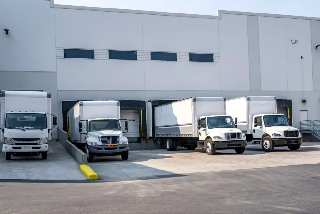 Several delivery trucks parked and aligned at a loading dock.