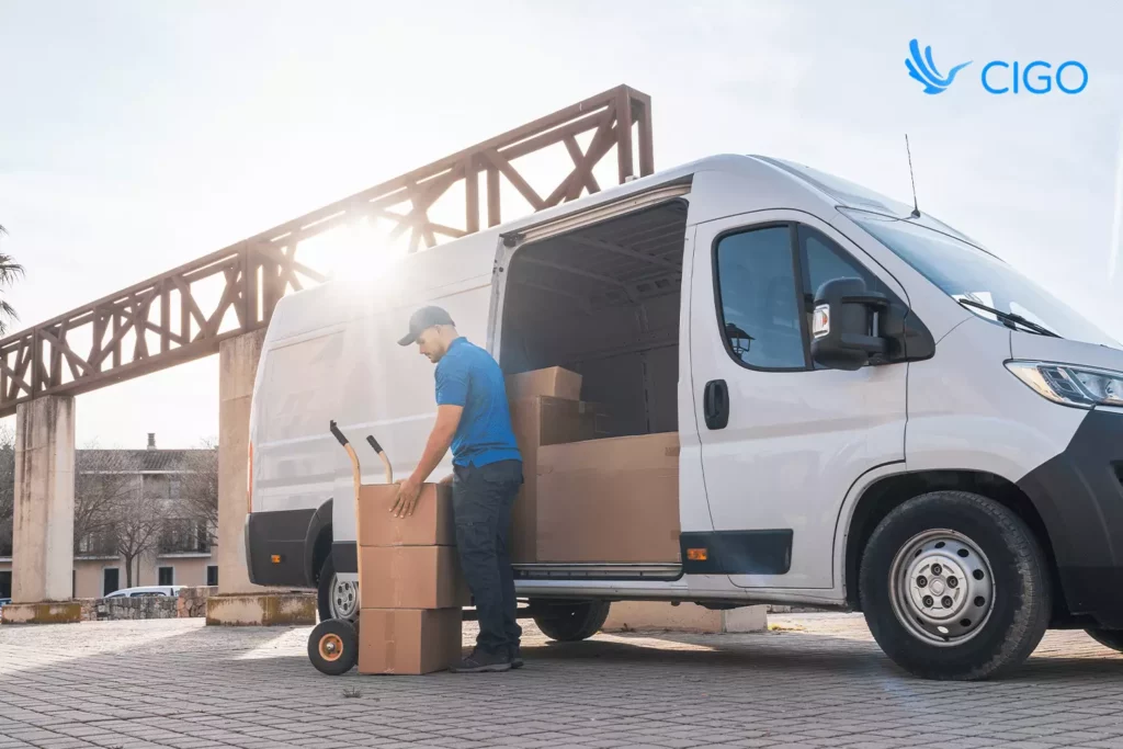 driver unloading packages with a truck beside the delivery van