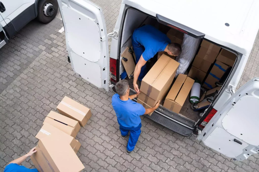 Delivery team in blue uniforms loading cardboard boxes into a van