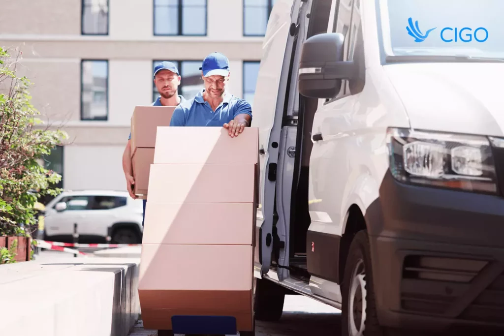 Two delivery professionals unloading boxes with a hand truck, representing streamlined operations and coordinated routing through last-mile delivery software