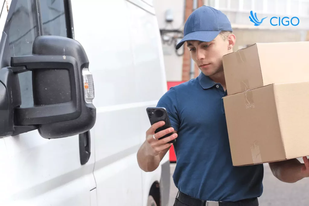 Delivery driver carrying parcels and checking mobile route app linked to Storis and NetSuite