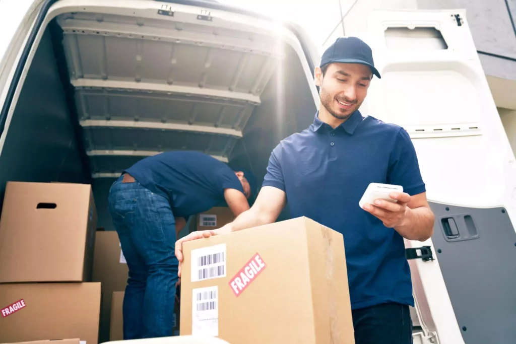 Courier checking a handheld device while unloading parcels