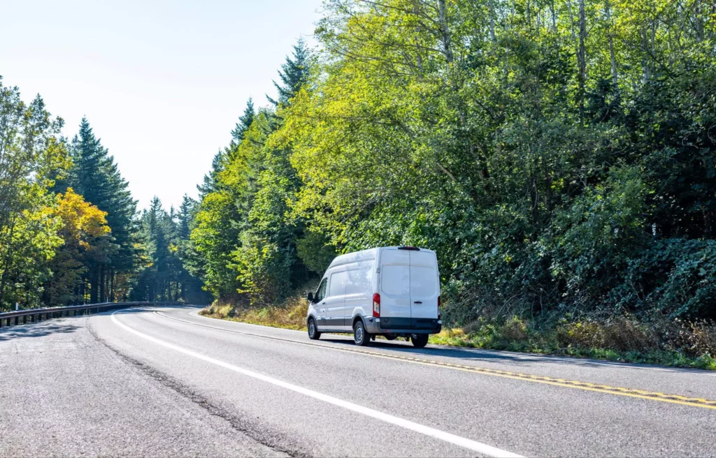 Long-wheelbase delivery van driving a rural highway