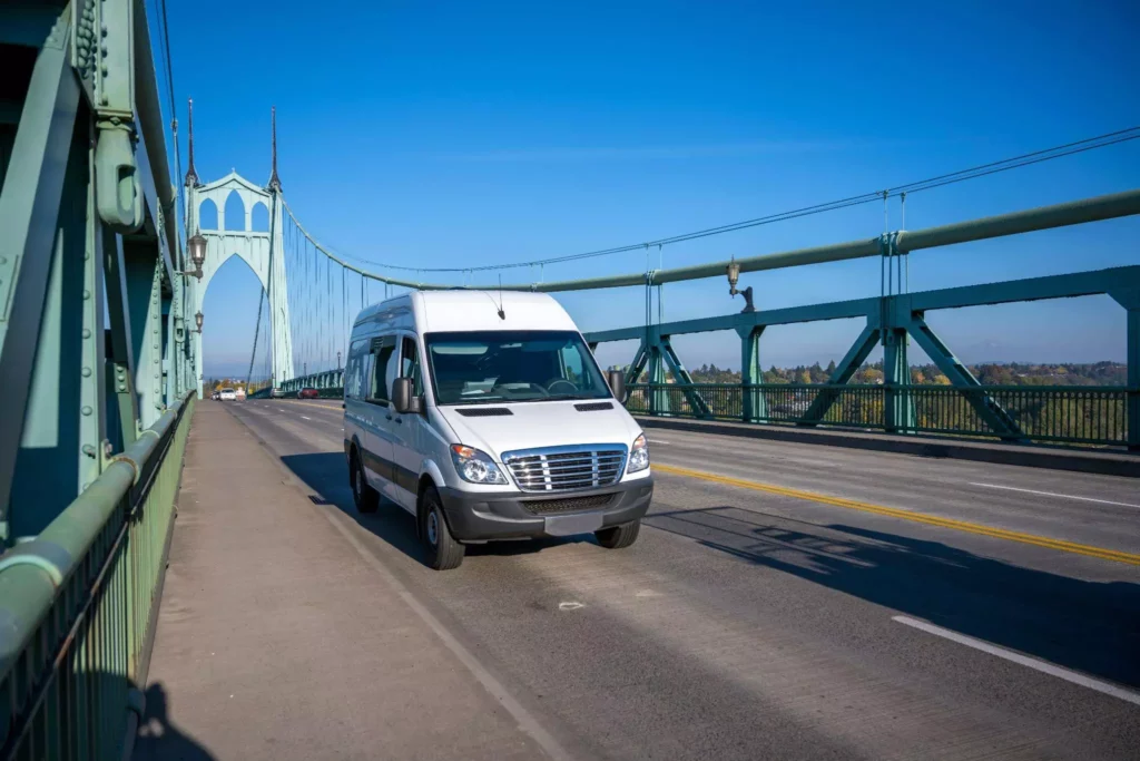 Delivery van crossing a steel bridge on a sunny day, symbolizing dynamic route optimization and ETA recalculations within connected delivery software