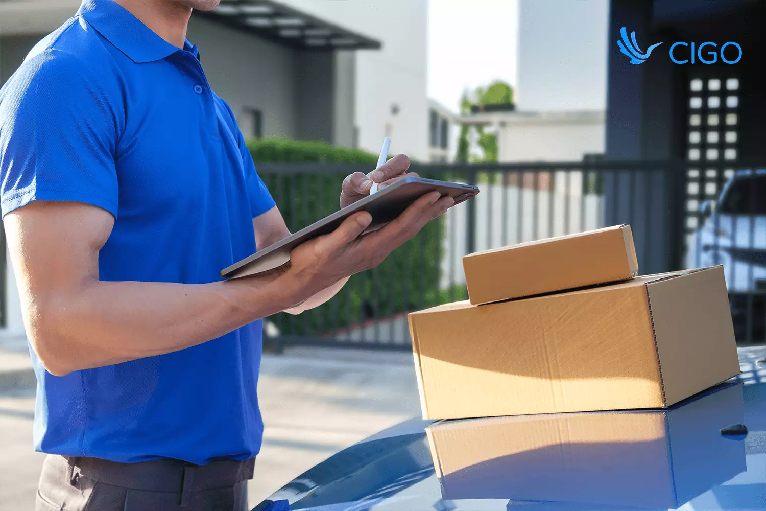Delivery driver updating tracking app beside packages