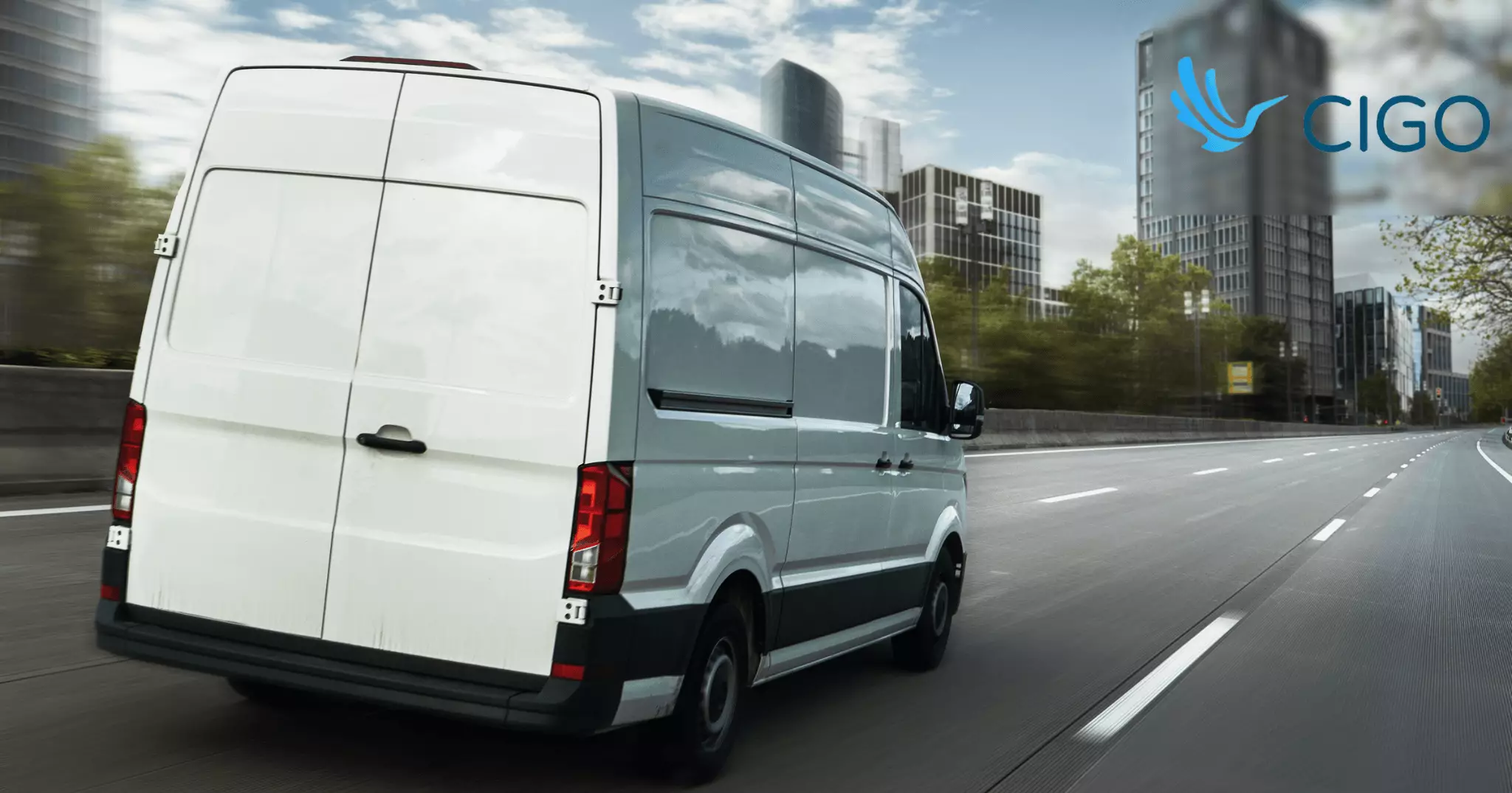 White delivery van navigating city road with buildings in background