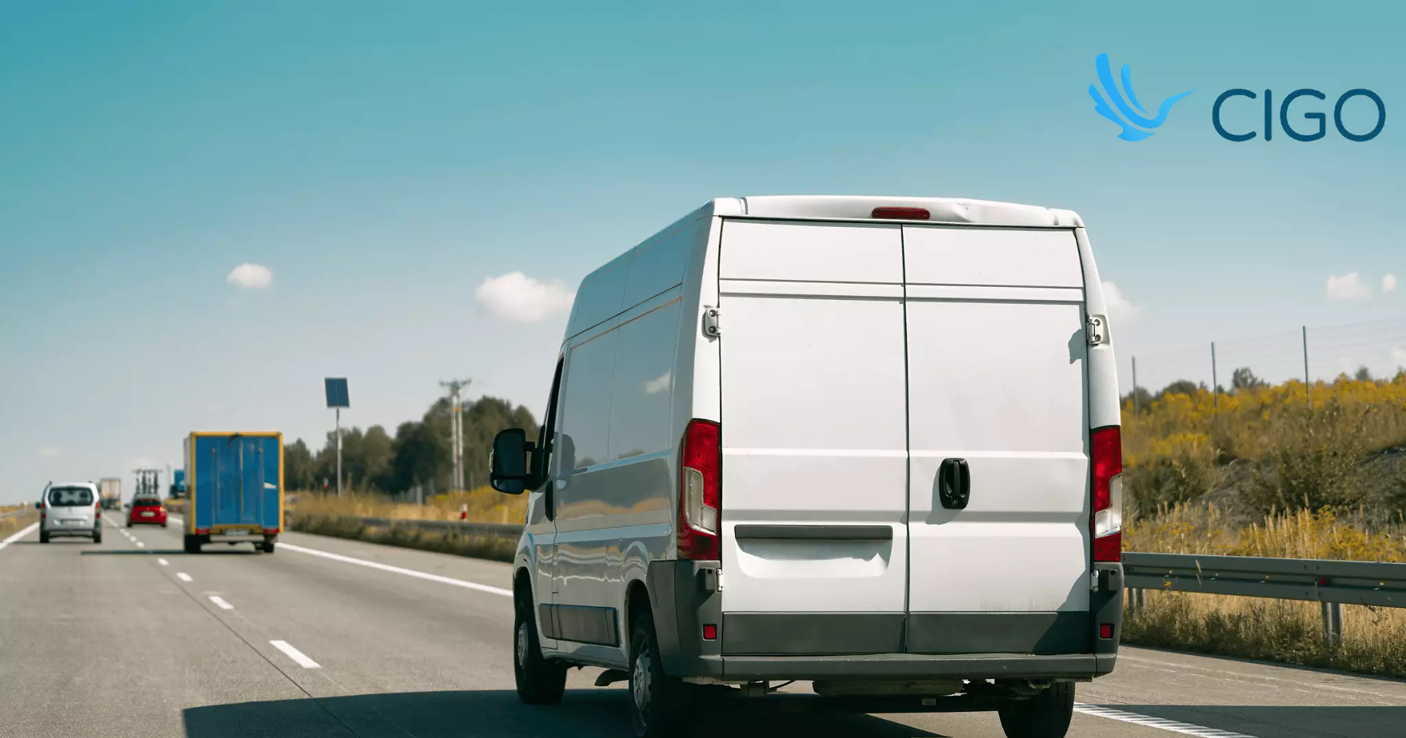 White delivery van driving on open highway viewed from behind