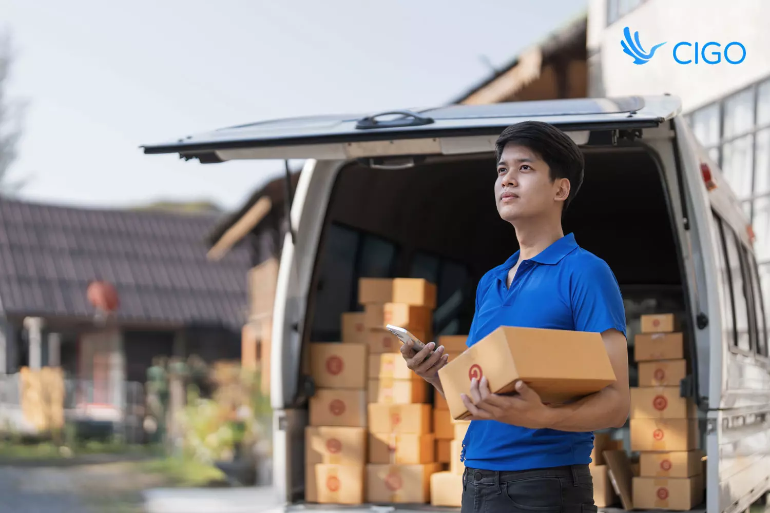Delivery driver checking phone with fully loaded van at residential stop