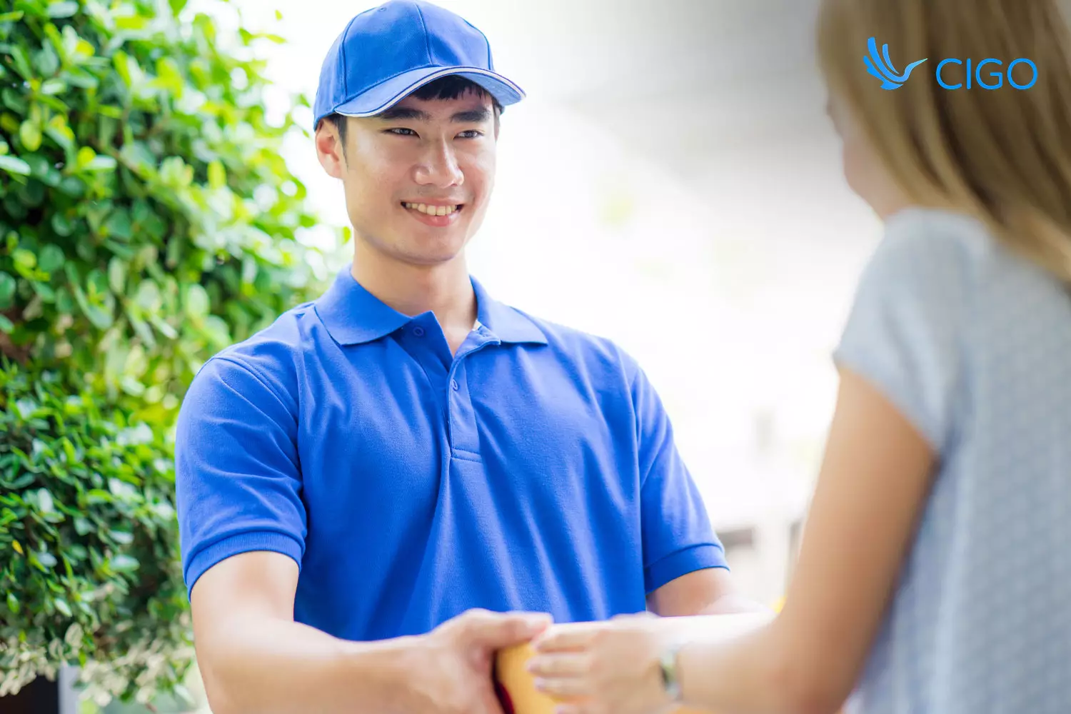 Delivery driver handing package to customer at door