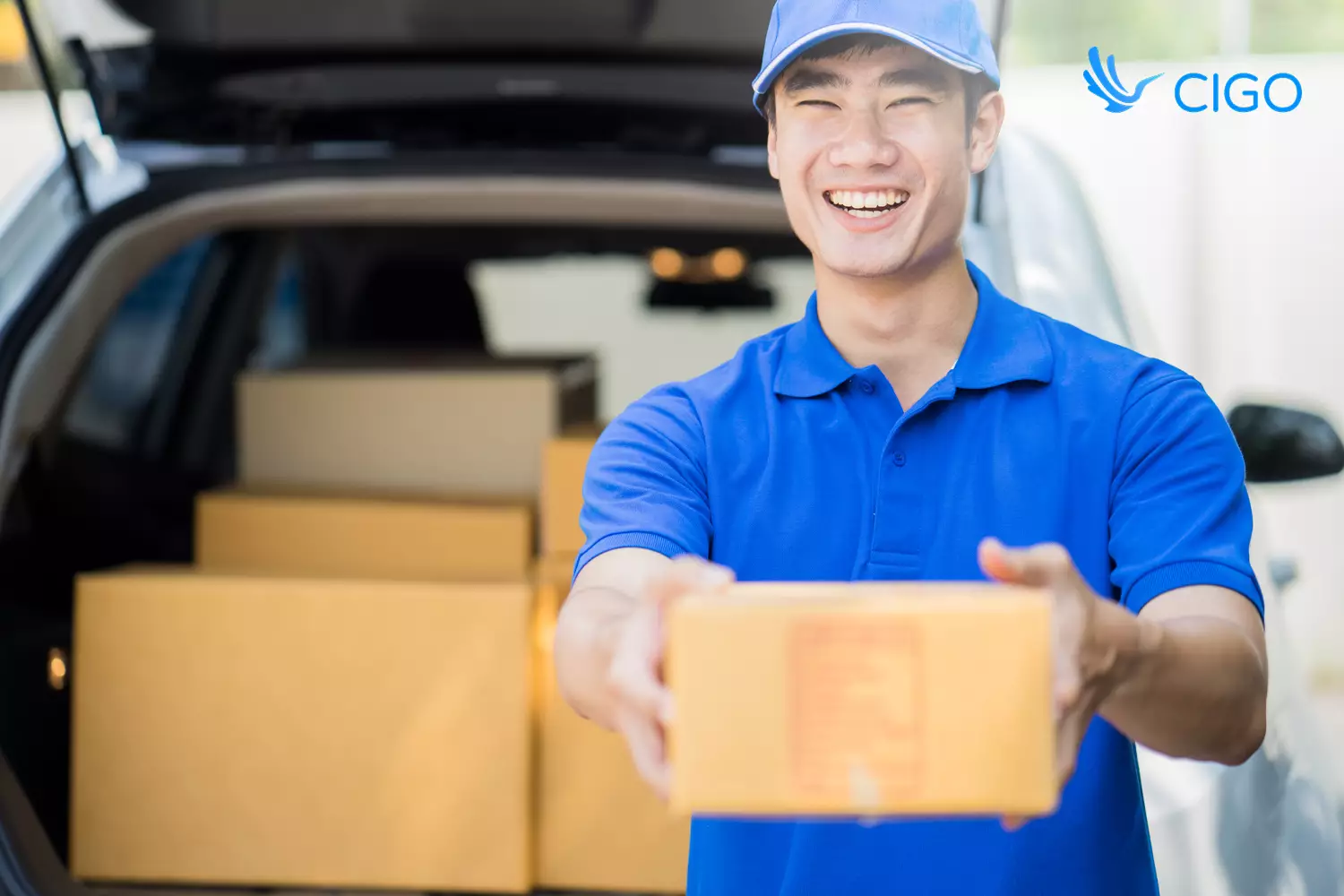 Delivery driver unloading package from vehicle trunk