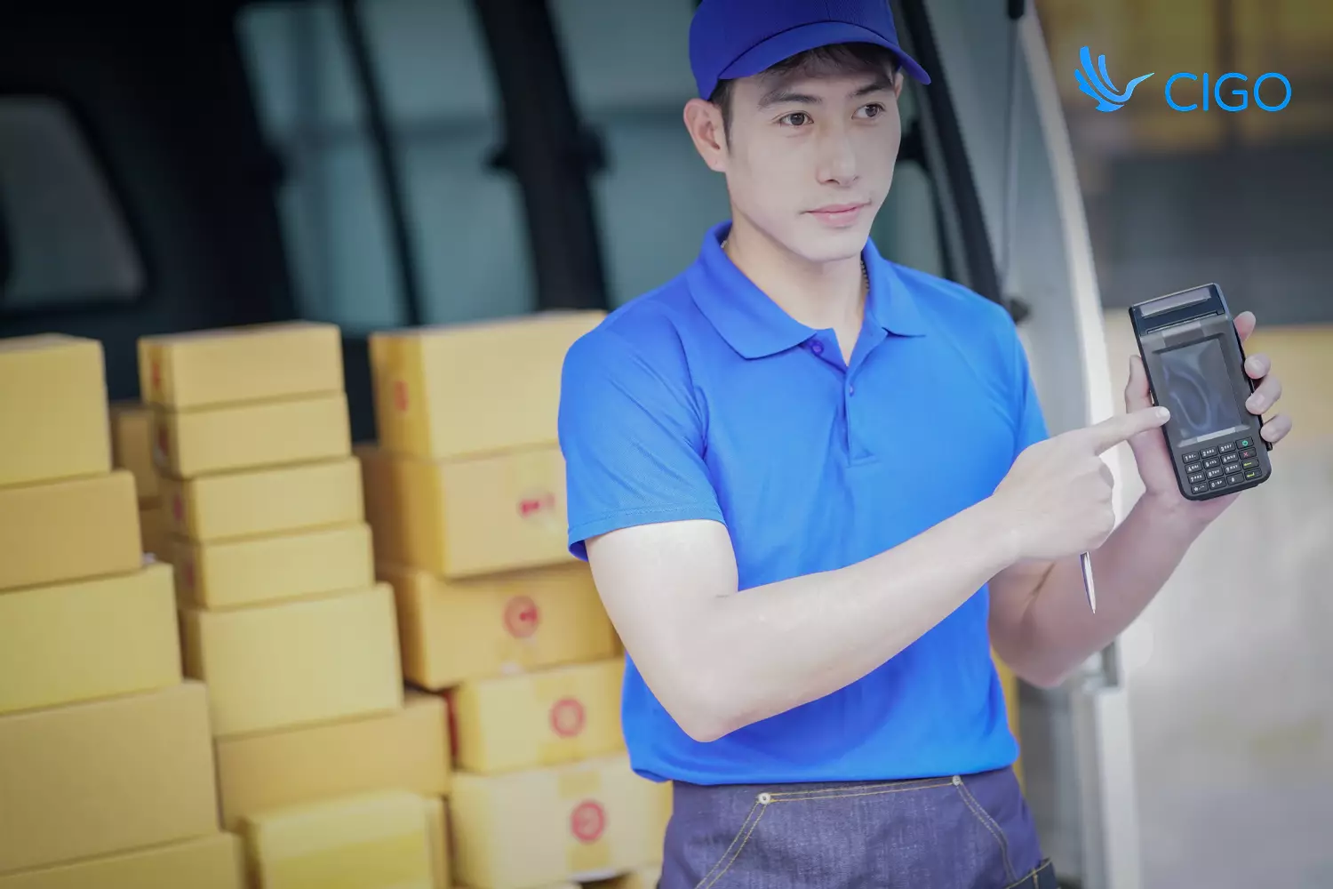 Delivery driver using handheld dispatch device beside stacked packages