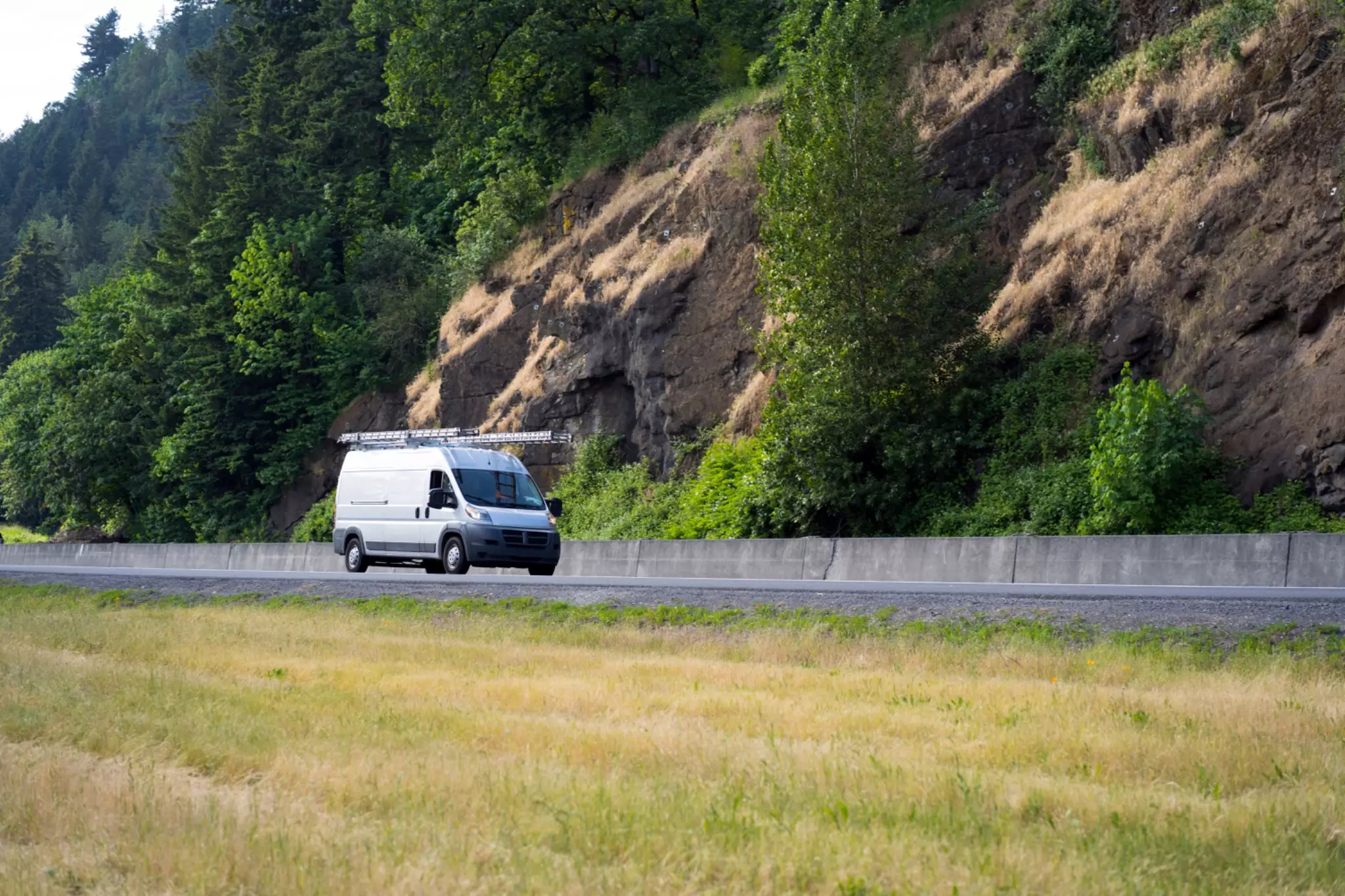 Delivery driver in blue uniform driving van with packages on seat 