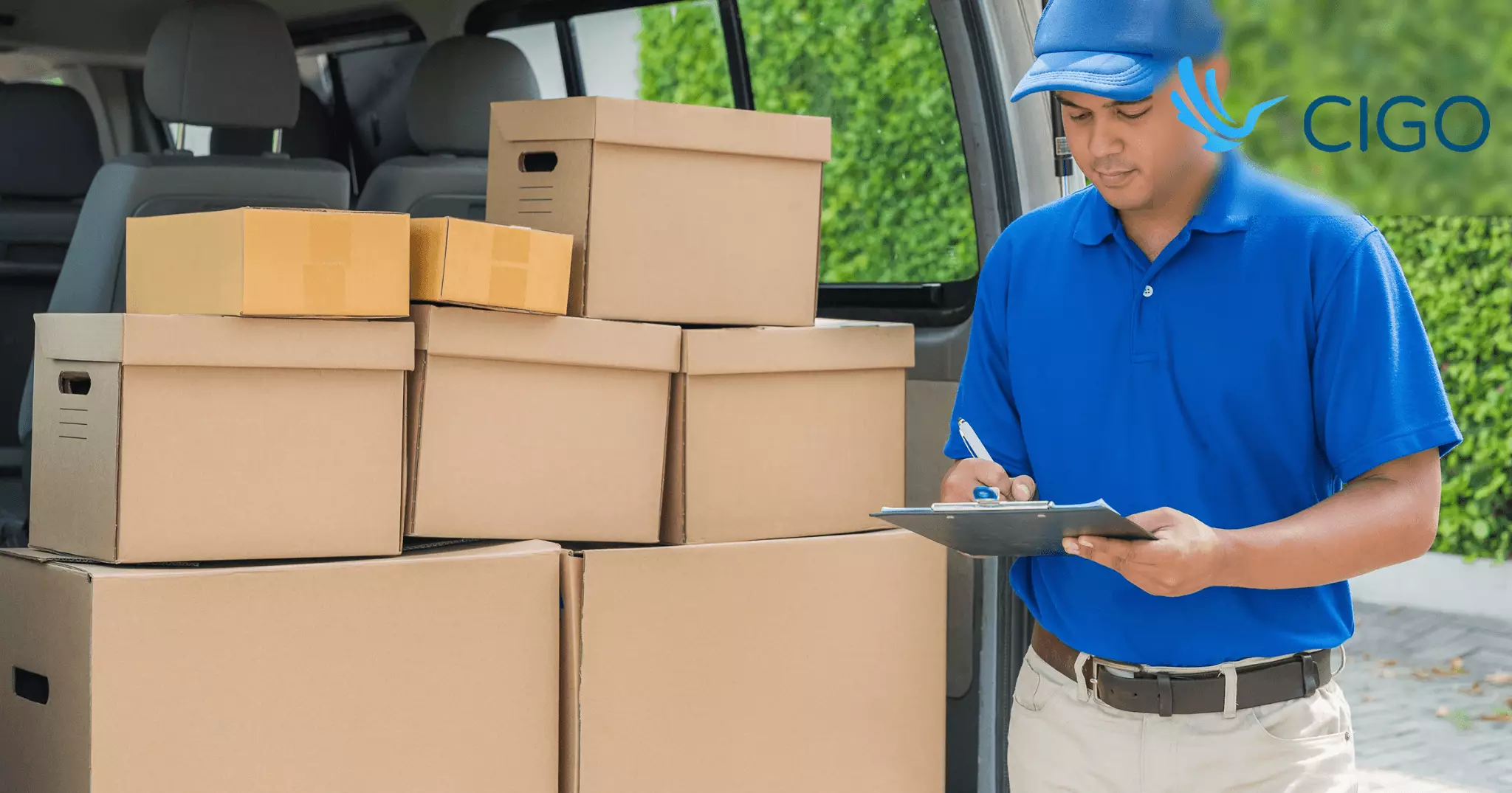 Delivery driver reviewing clipboard next to packages in van