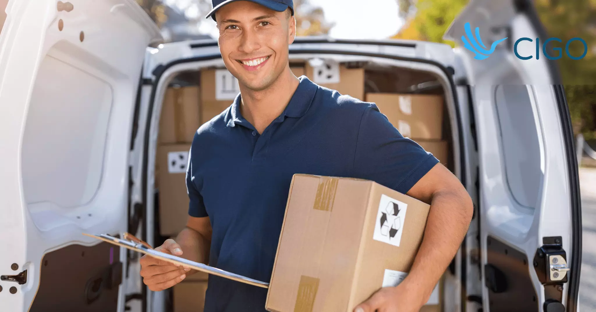 Delivery driver holding package and clipboard at van