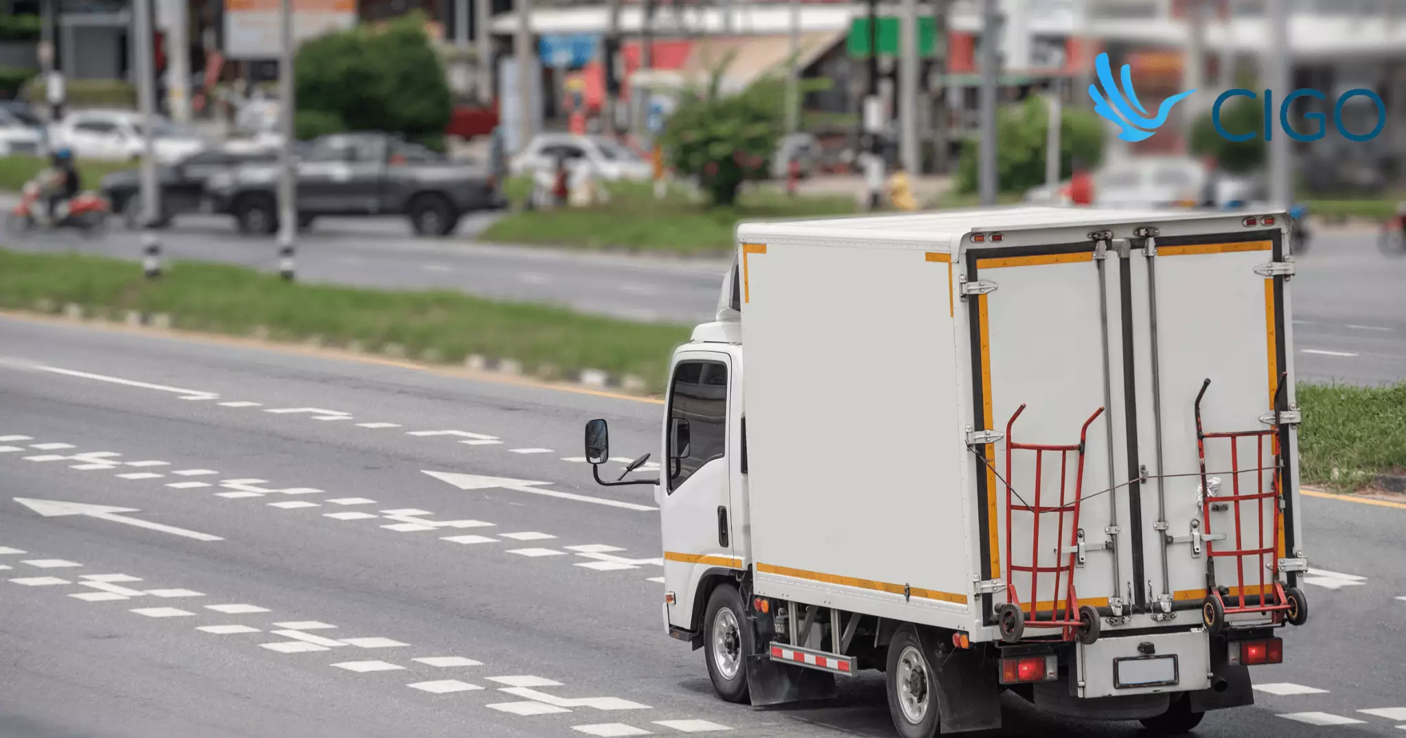 White box truck with hand truck navigating busy city road