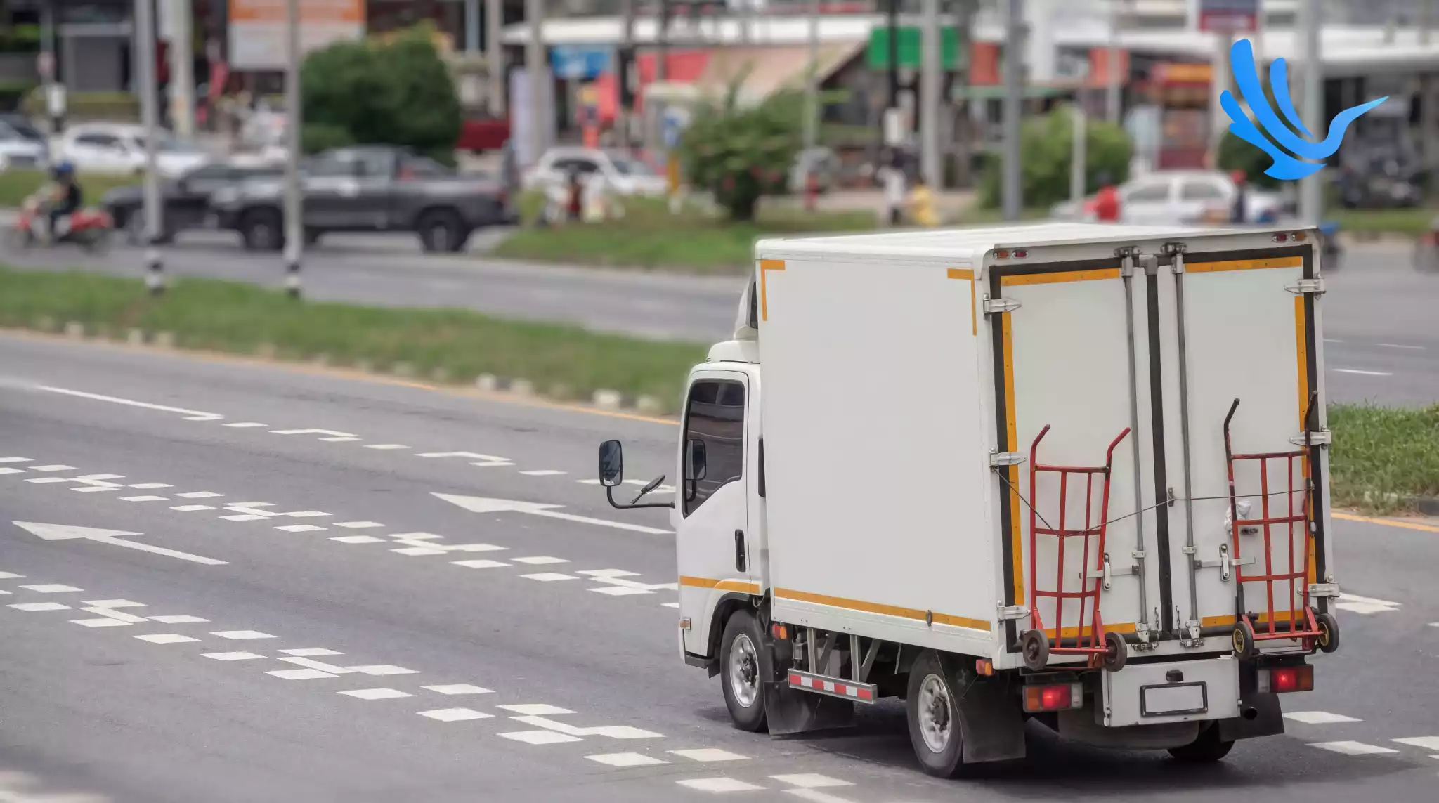 White box truck with hand truck navigating busy city road