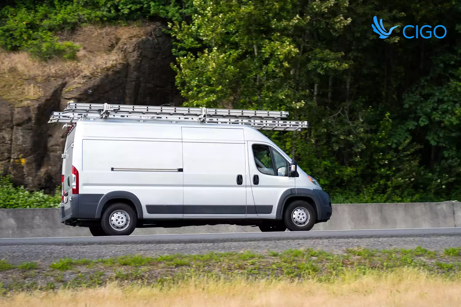 White fleet cargo van with roof rack driving on delivery route
