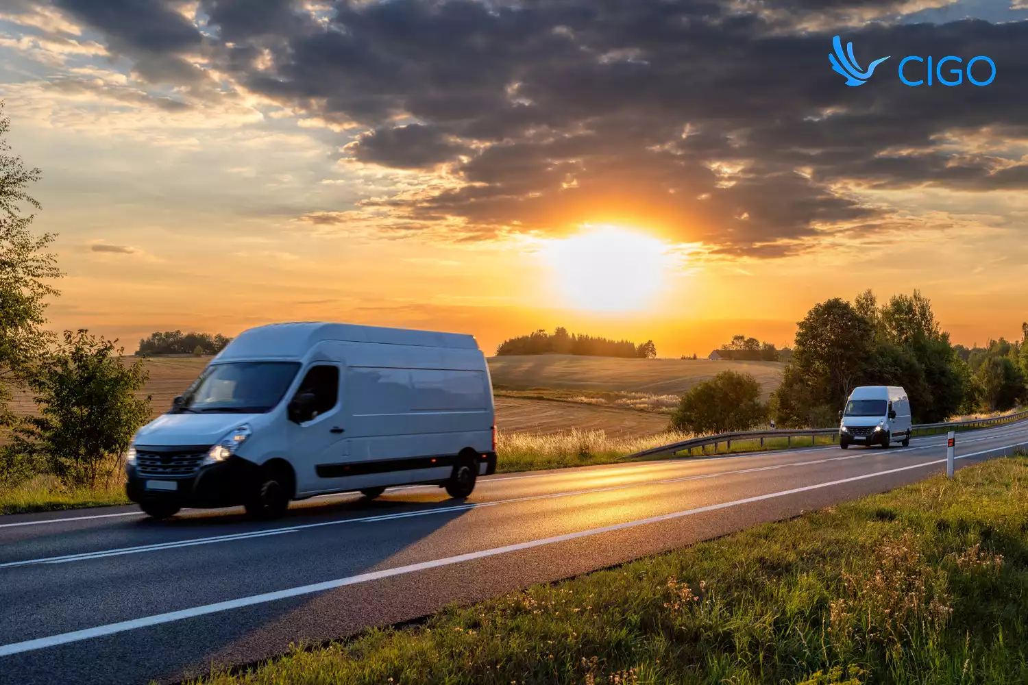 Two white fleet delivery vans on scheduled rural route at sunset